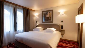 A hotel room with a large bed, two bedside lamps, a painting on the wall, and a red carpet.