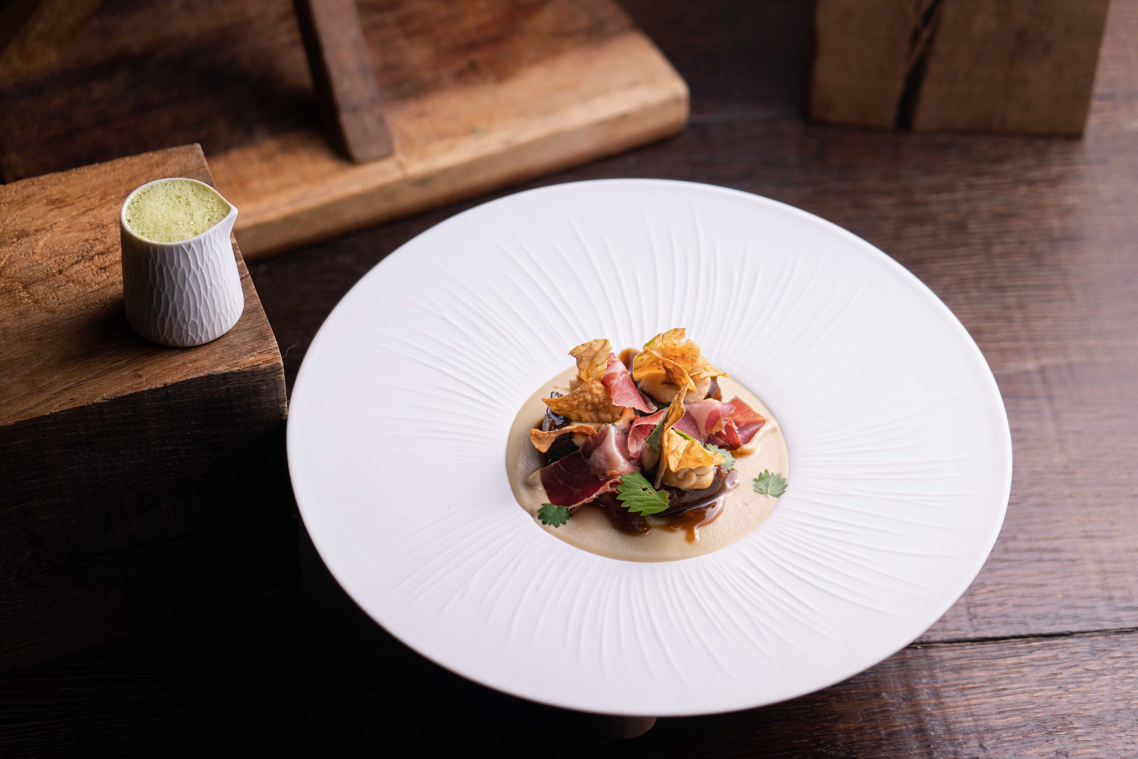 A white plate with a gourmet dish on a wooden table.