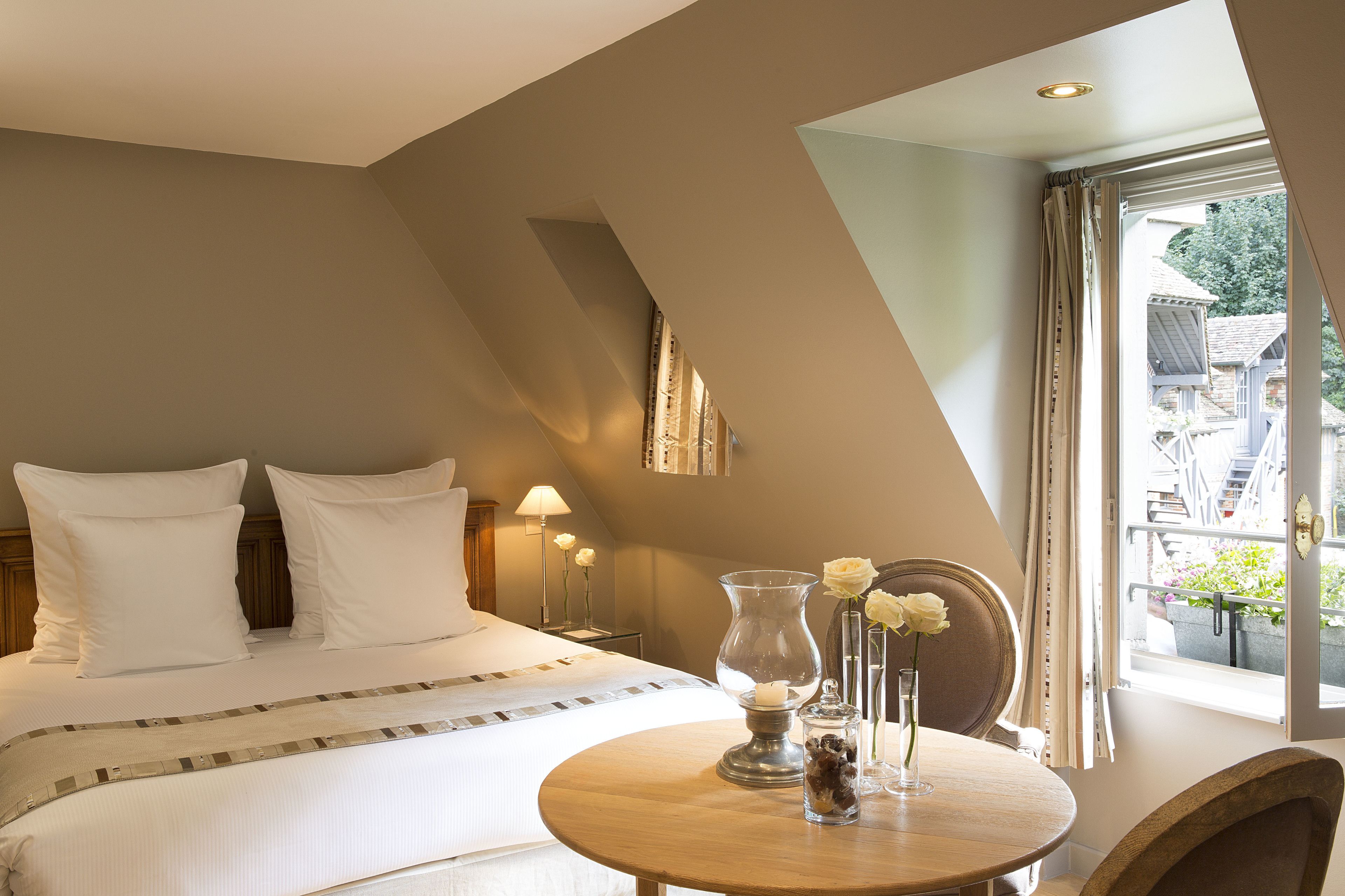 Ein Schlafzimmer mit Bett, Nachttisch, Lampe und Blick ins Freie.