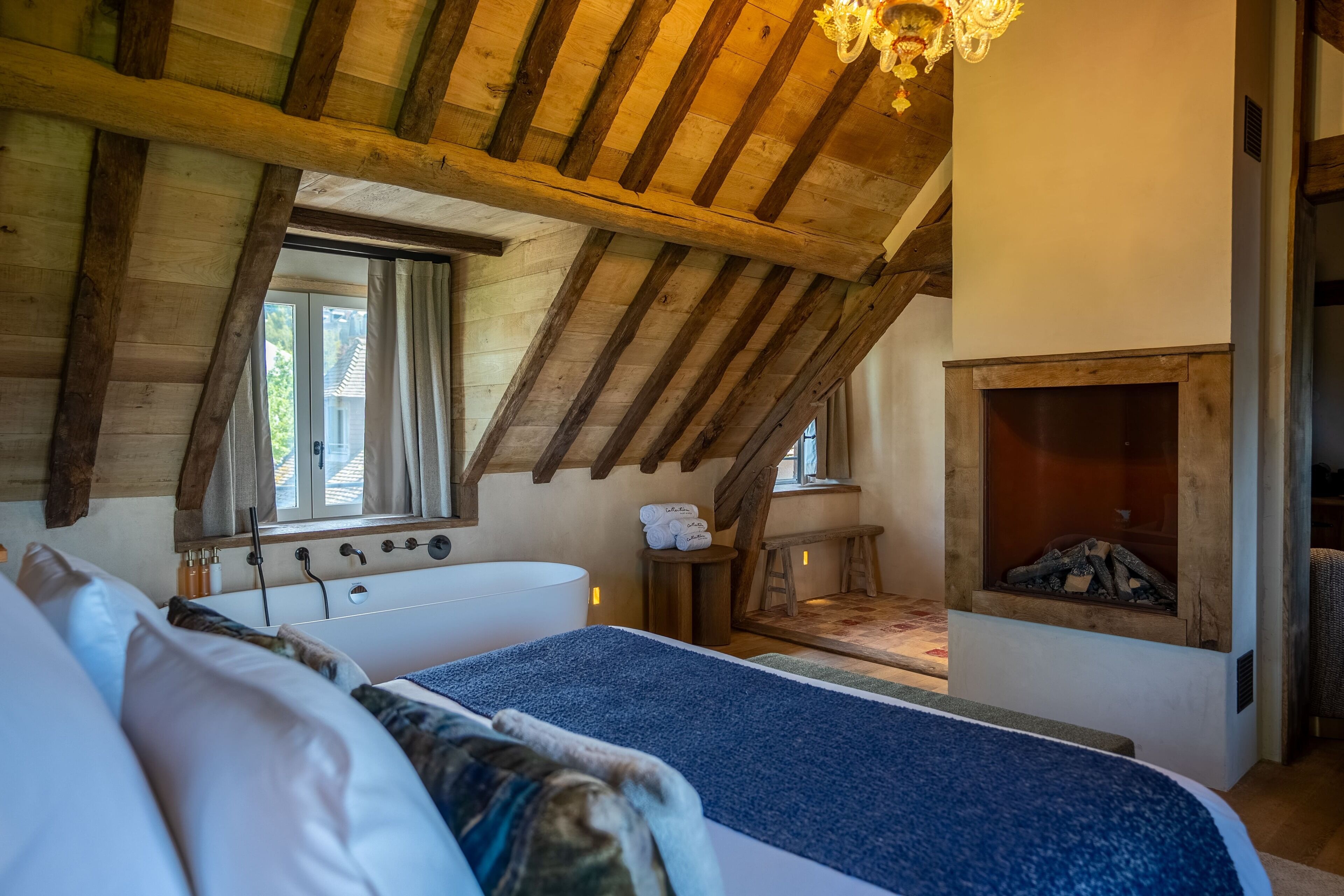 Ein Schlafzimmer mit Holzboden, einem großen Bett, einem Kamin und einem Fenster.
