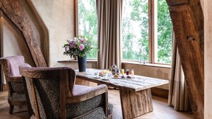Une table à manger en bois rustique, avec des chaises, un vase de fleurs et des aliments pour le petit-déjeuner.