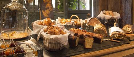 A breakfast buffet with various breads, pastries, and jams.
