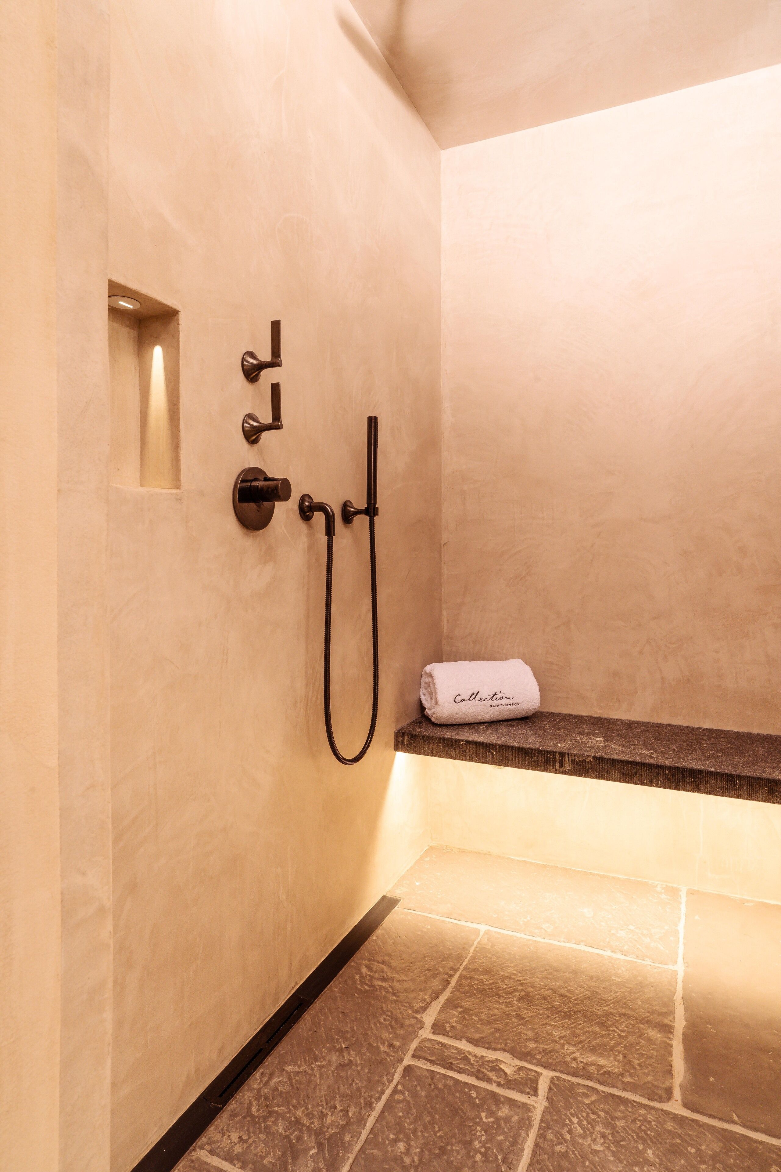 Een badkamer met een douche, een handdoekhouder en een klein plankje.