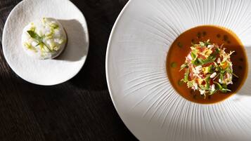 Two plates of food, one with a white sauce and the other with a red sauce, on a dark wooden table.