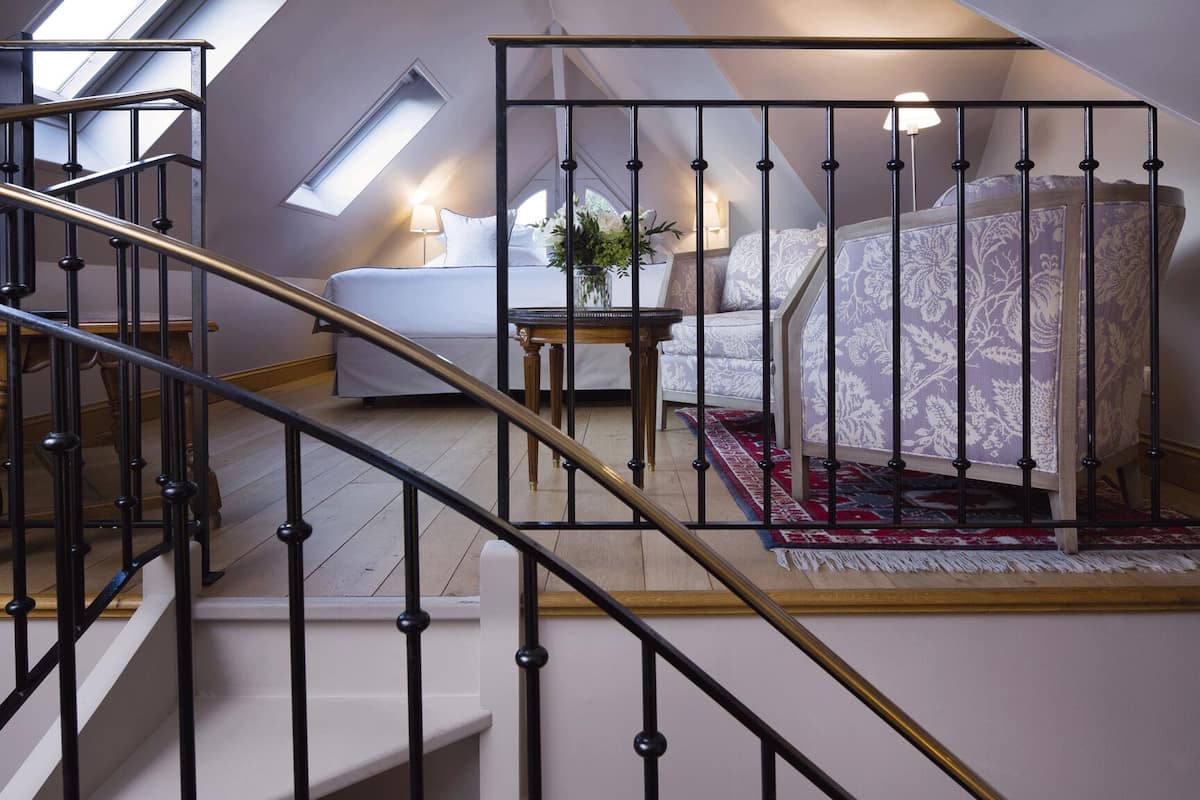 A bedroom with a bed, a nightstand, a lamp, and a window.