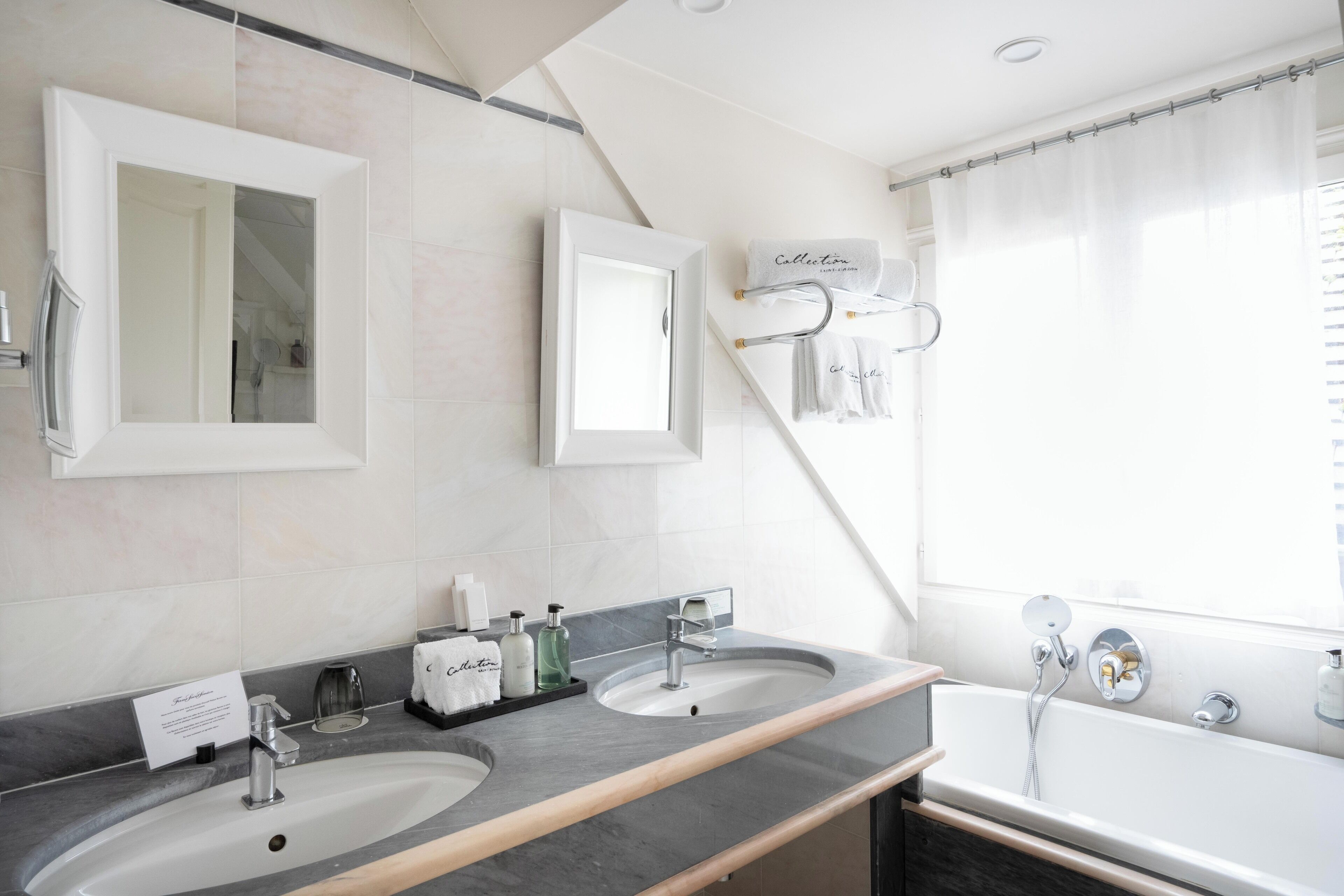 Un baño moderno con dos lavamanos, una bañera y una ducha.