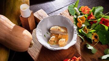 Une table en bois sur laquelle se trouve un bol blanc contenant un plat, une carafe en bois et une courge.