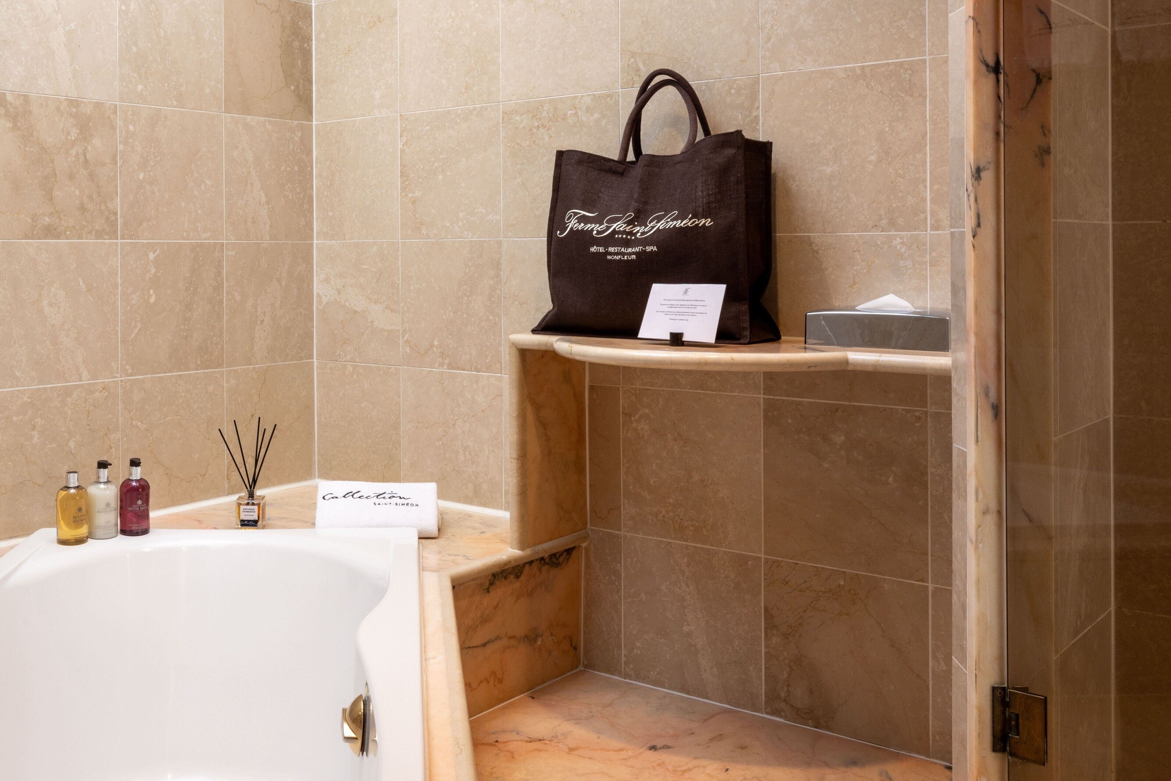 Et badeværelse med et badekar, en hylde med en brun tote taske, og toiletartikler.