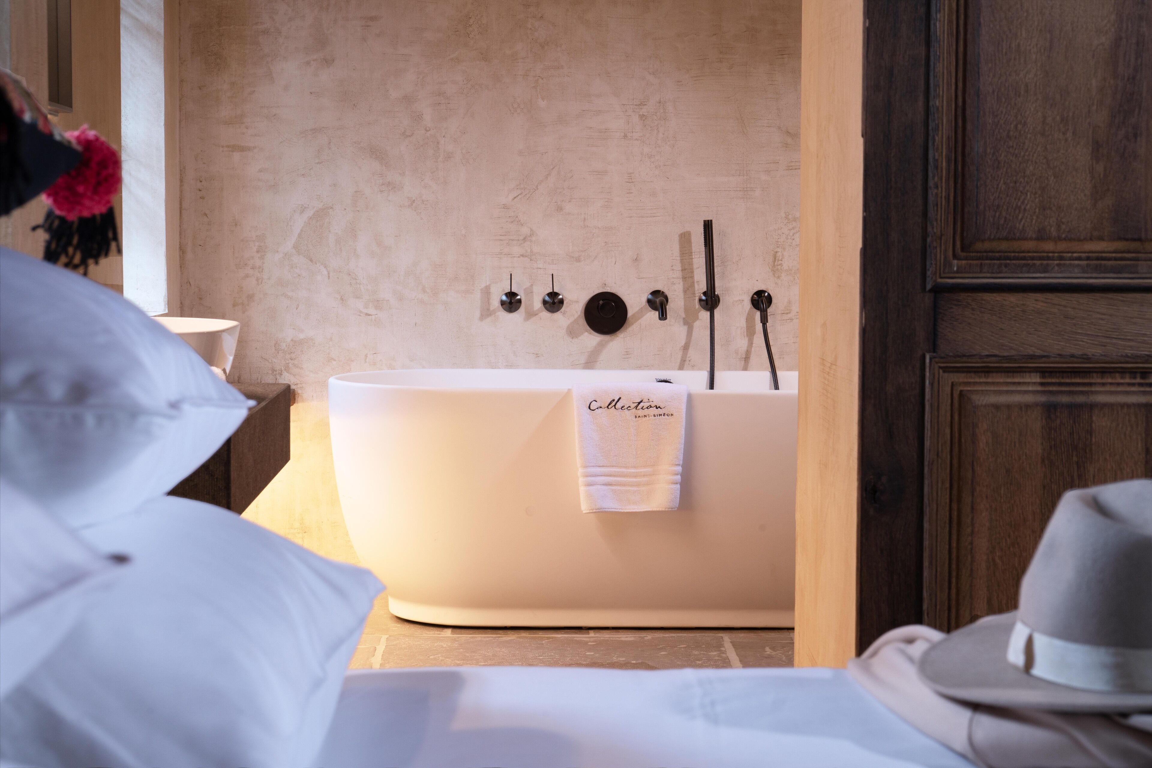 A modern bathroom with a freestanding bathtub, a towel rack, and a wooden door.
