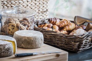 A wicker basket filled with assorted pastries and a glass jar of cookies.