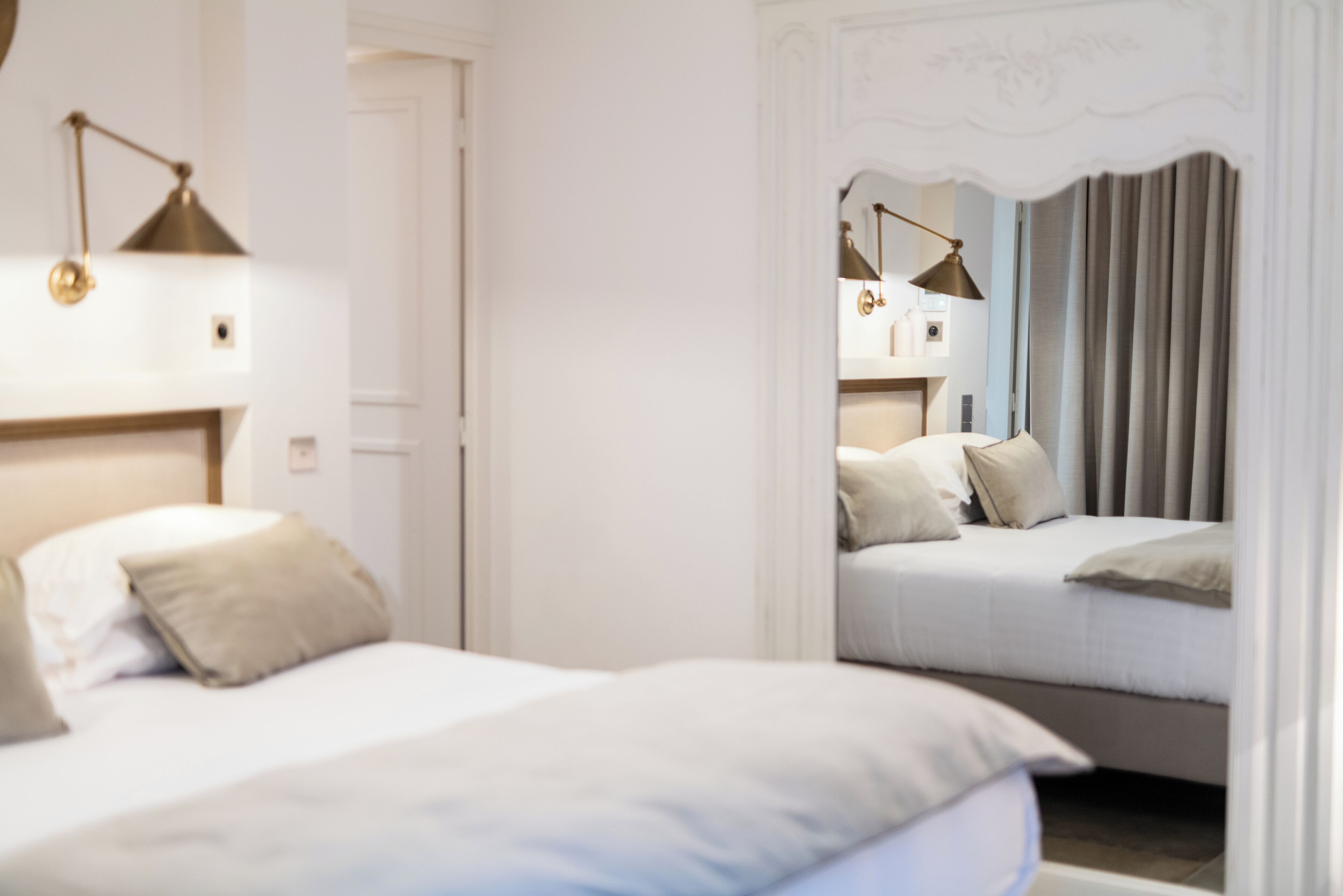 Une chambre avec deux lits, un miroir et une lampe.