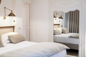 A bedroom with two beds, a mirror, and a lamp.