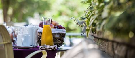 A breakfast table with a pitcher, cups, a glass of orange juice, and fresh fruit.
