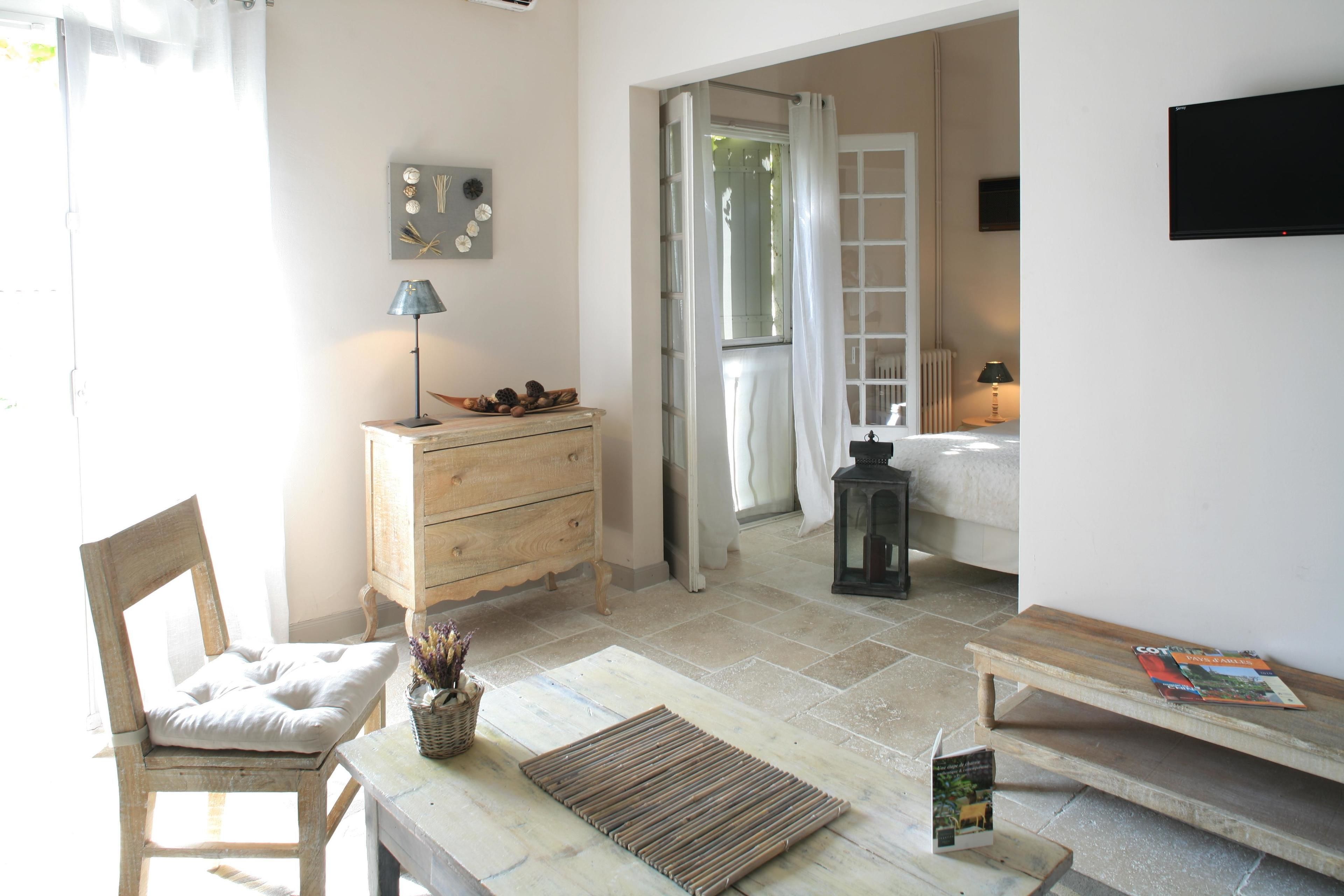 Una habitación acogedora con una silla de madera, una mesita, un aparador y una ventana con cortinas.