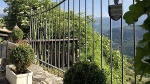 Una cerca de metal con un letrero con forma de mano, plantas en macetas y vistas de un paisaje montañoso.