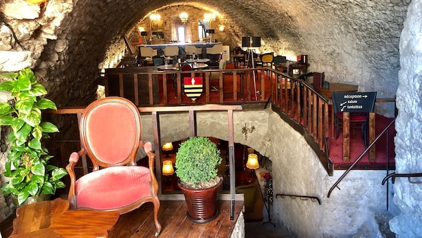 Un restaurante subterráneo con techo de piedra, muebles de madera y un mostrador de recepción.