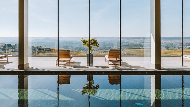 Un área de piscina interior moderna con vistas despejadas a un paisaje a través de amplios ventanales.