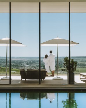 Una piscina techada, una piscina al aire libre, sombrillas