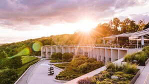 Un hotel moderno con jardín en la azotea, jardines escalonados y vistas despejadas de las colinas circundantes.