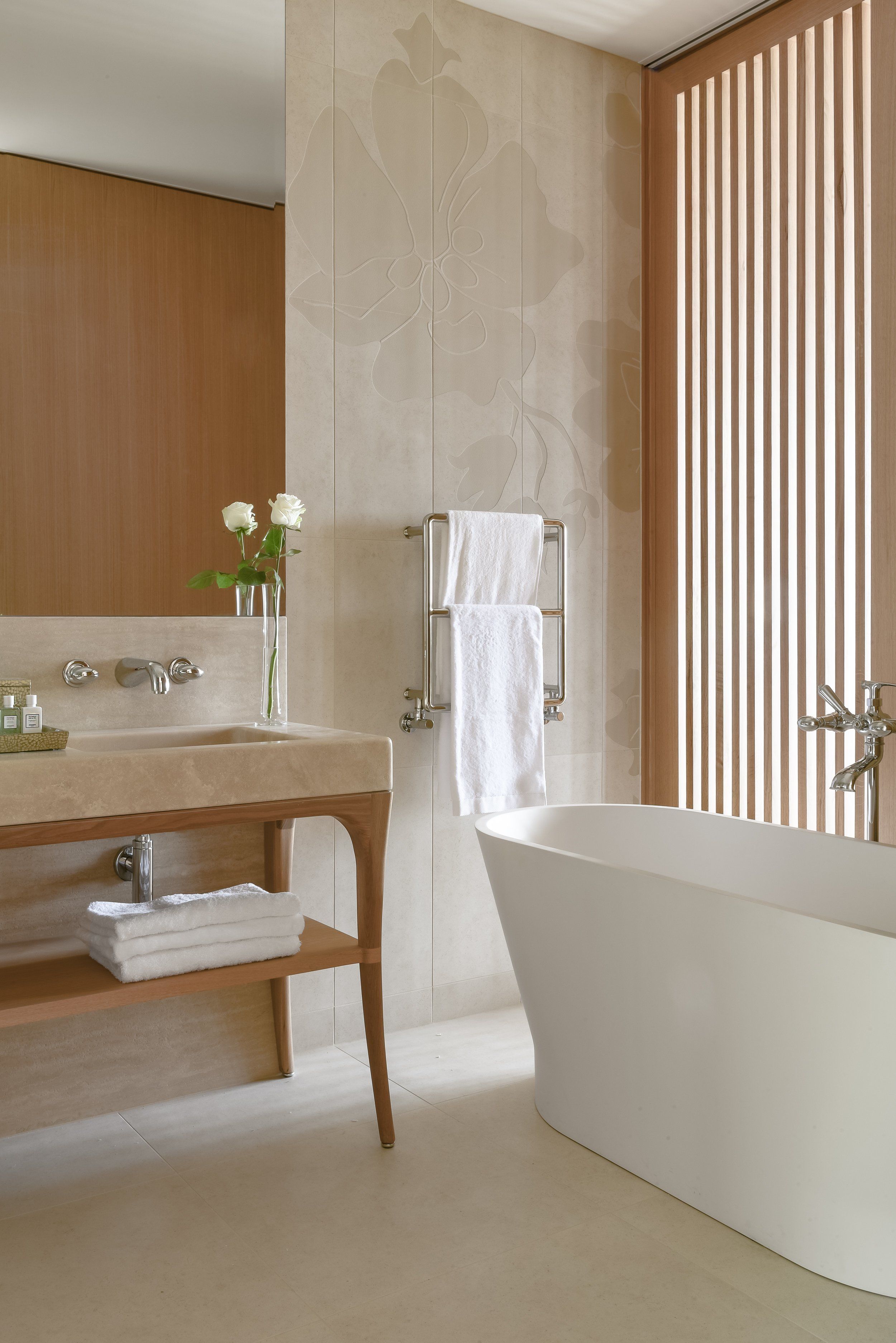 Une salle de bain moderne avec une baignoire sur pieds, un meuble-lavabo avec un miroir et un porte-serviettes.