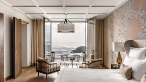 Una habitación de hotel con una cama grande, un escritorio con lámpara, una silla y vistas al océano.