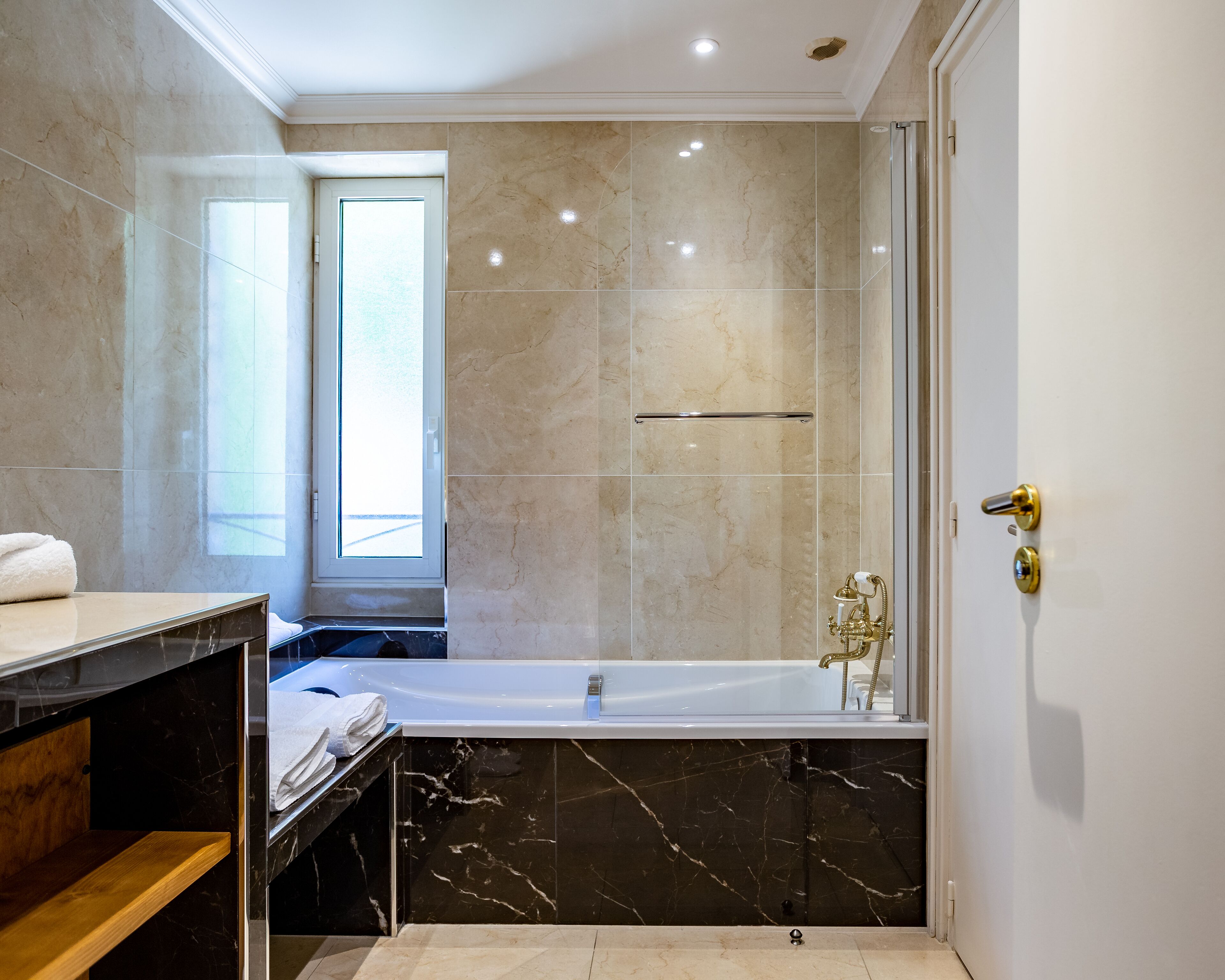 A modern bathroom with a bathtub, a shower, and a vanity with a towel.