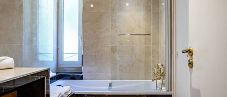 A modern bathroom with a bathtub, a shower, and a vanity with a towel.