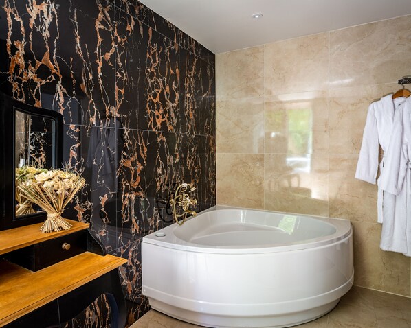 A modern bathroom with a freestanding bathtub, marble walls, and a wooden vanity.