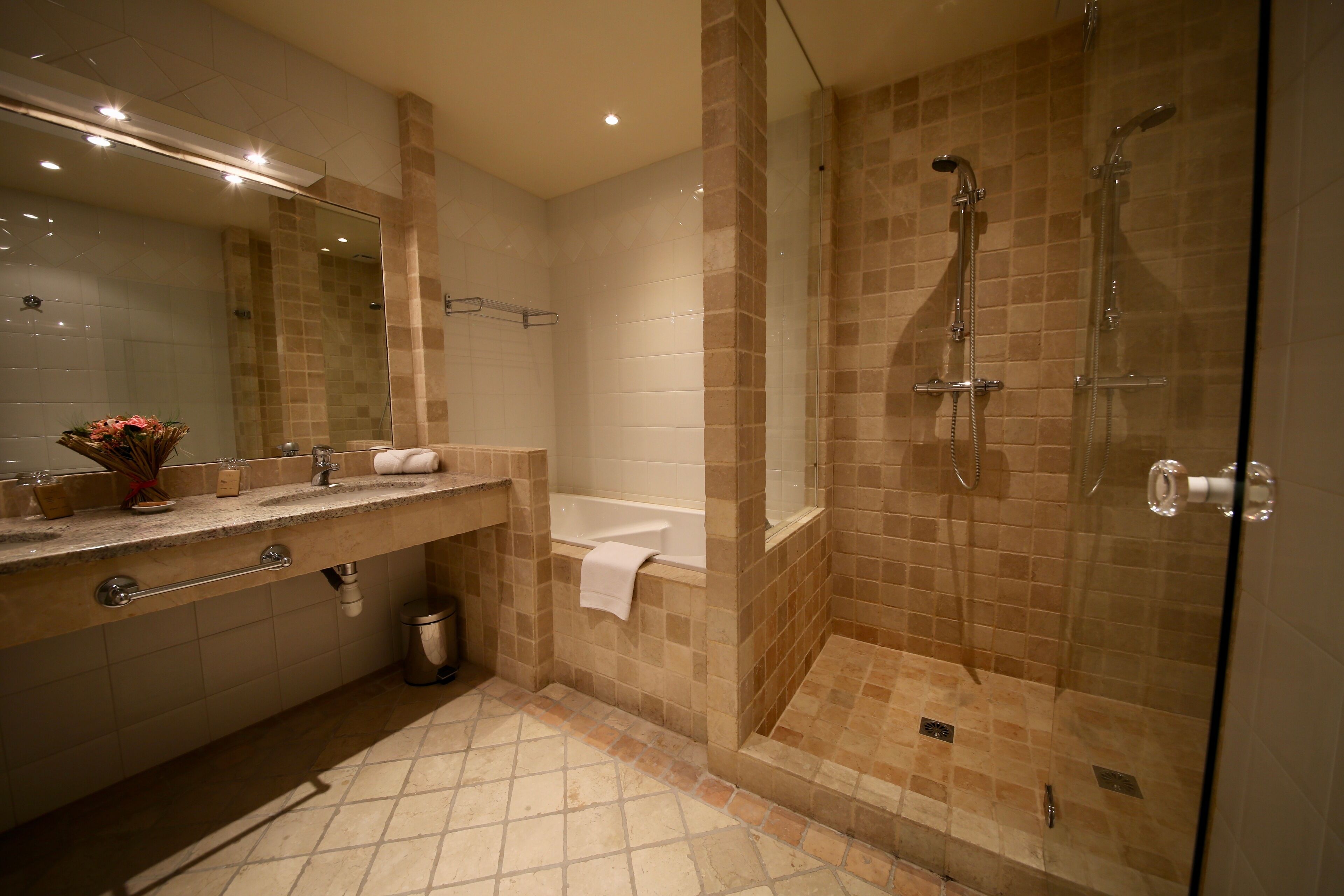Un baño moderno con ducha de vidrio, bañera y tocador con espejo y lavamanos.