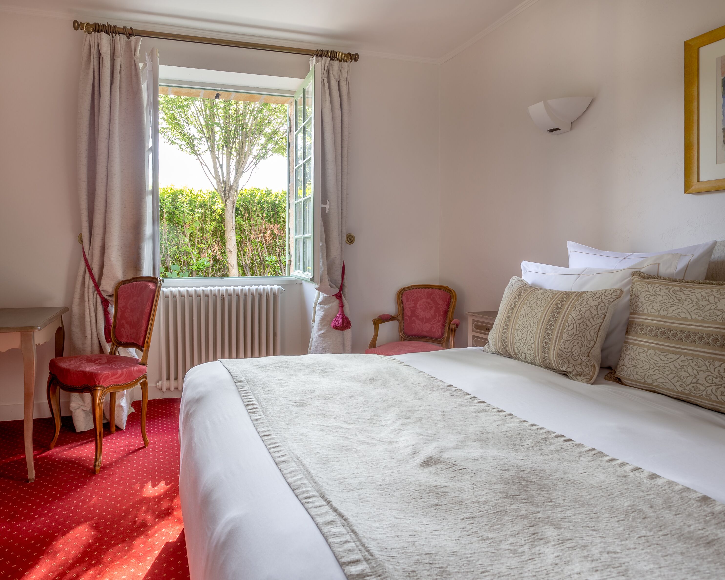 Una habitación de hotel con una cama grande, un escritorio, dos sillas y una ventana con cortinas.