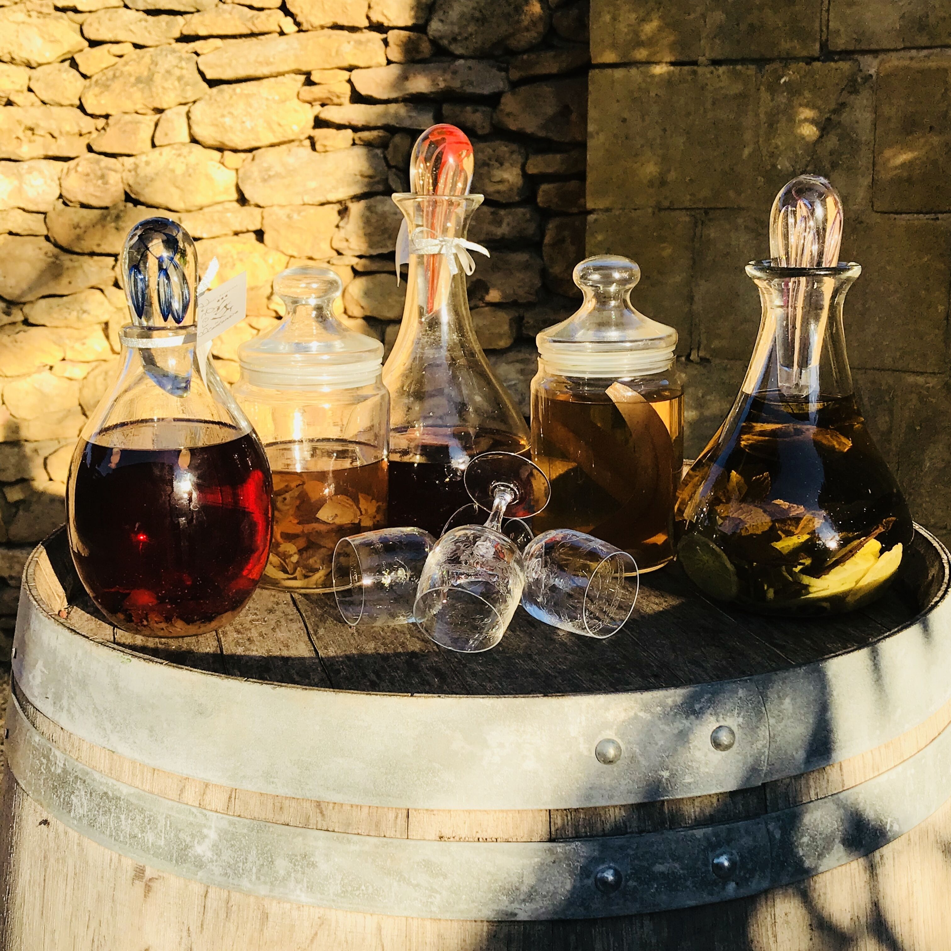 A wooden barrel with various glass containers and empty wine glasses on top.