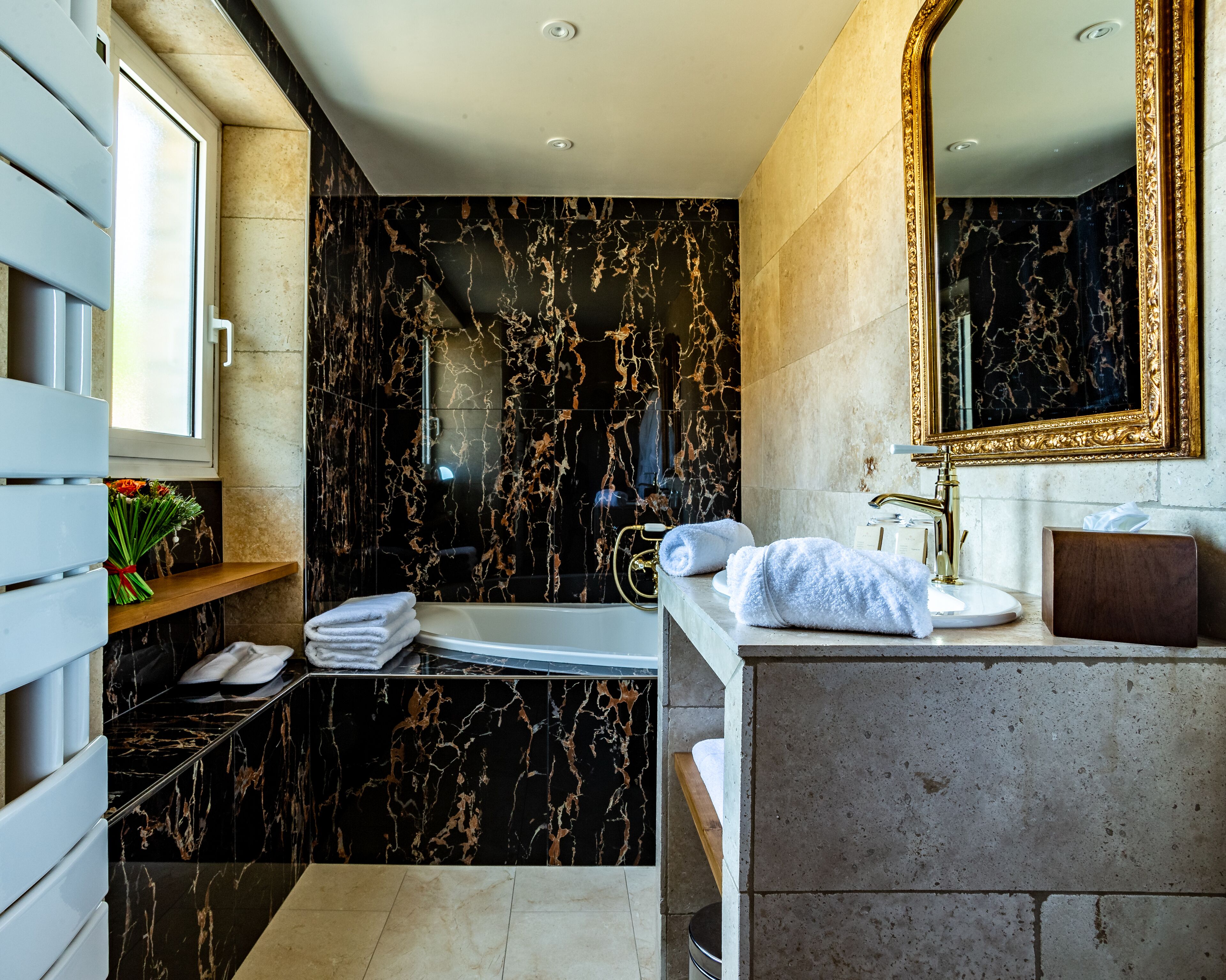 A modern bathroom with a marble vanity, a bathtub, and a large mirror.