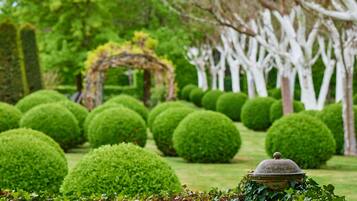 A well-manicured garden with neatly trimmed hedges and a stone structure.