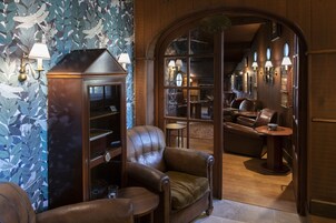 Um quarto acolhedor com poltronas de couro, um armário de madeira e uma grande janela em arco.