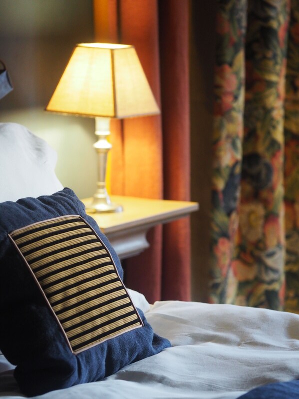 A bed with a striped pillow, a bedside lamp, and a floral curtain. - Château de Mercuès (Mercues)