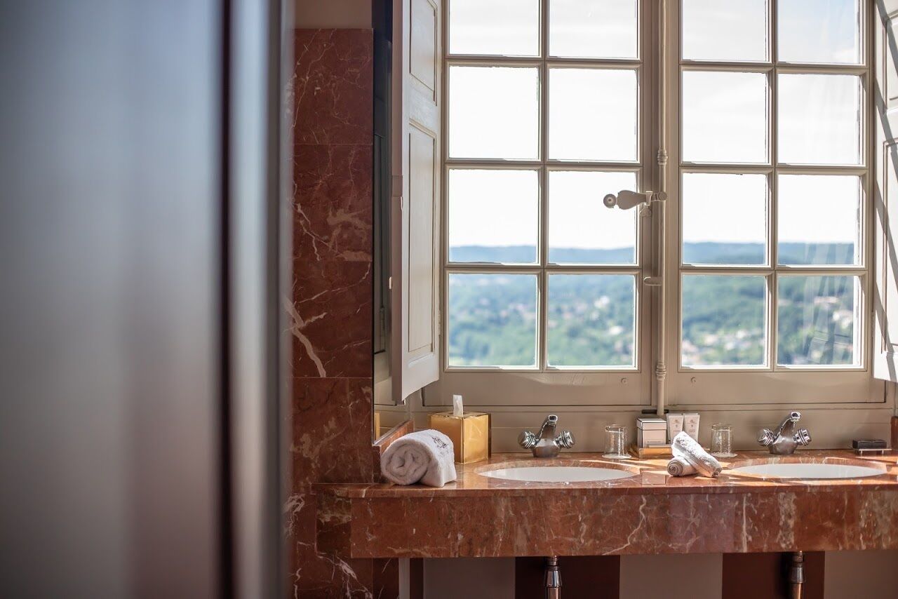 Une salle de bain avec une grande fenêtre, deux lavabos et une serviette posée sur le comptoir.