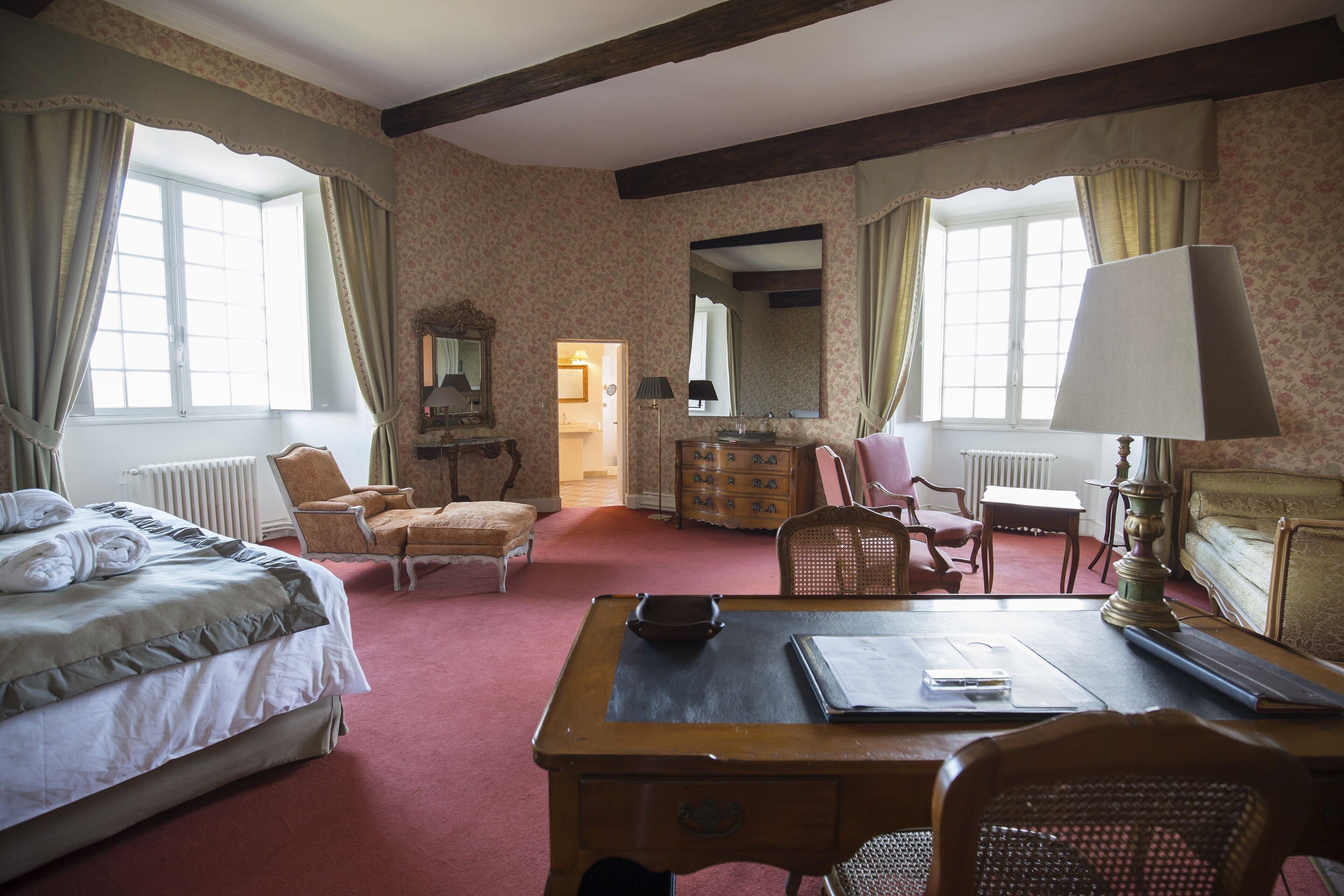 Une chambre d’hôtel comprenant un lit, un bureau, une chaise, une commode et un miroir.