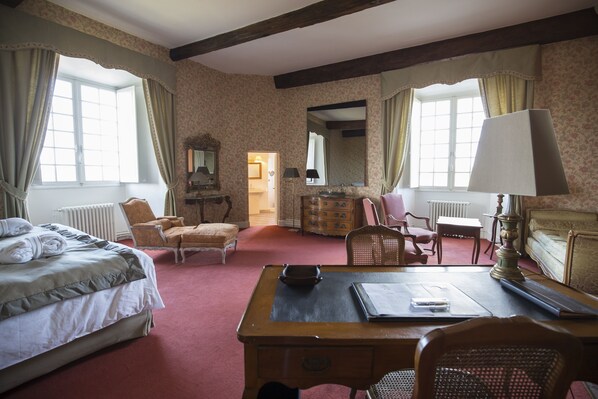 A hotel room with a bed, a desk, a chair, a dresser, and a mirror.