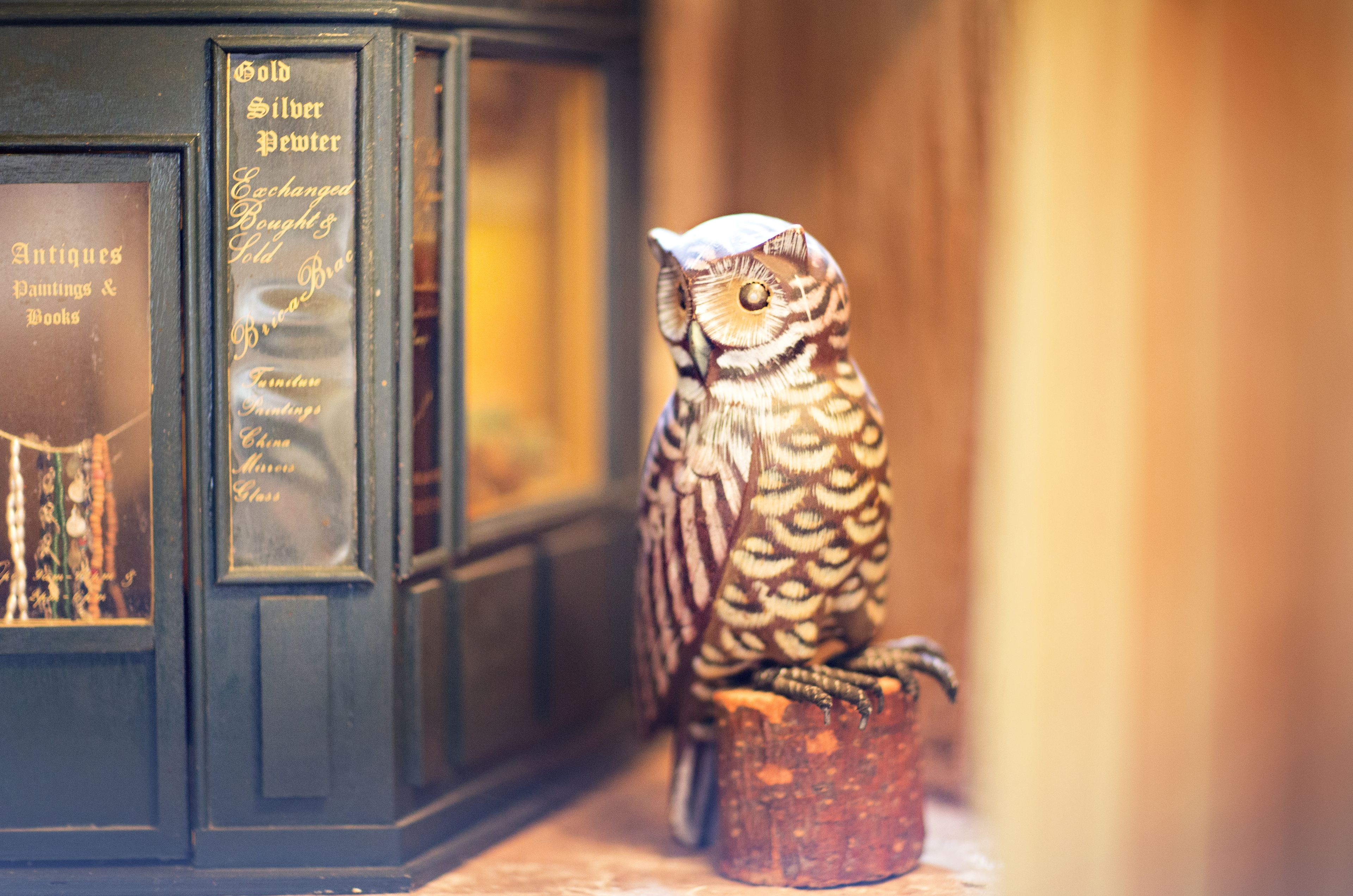 A decorative owl sculpture on a wooden base, positioned next to a display case with glass doors.