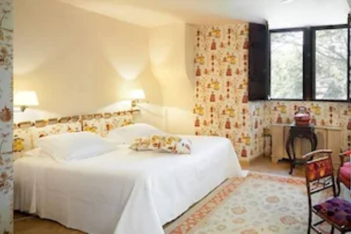 A bedroom with a bed, a desk, a chair, and a mirror.