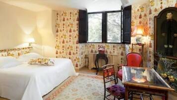 A bedroom with a bed, a desk, a chair, and a mirror.