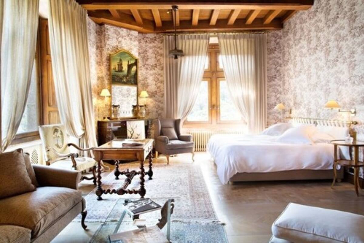 A room with a bed, a sofa, a chair, a table, and a lamp.