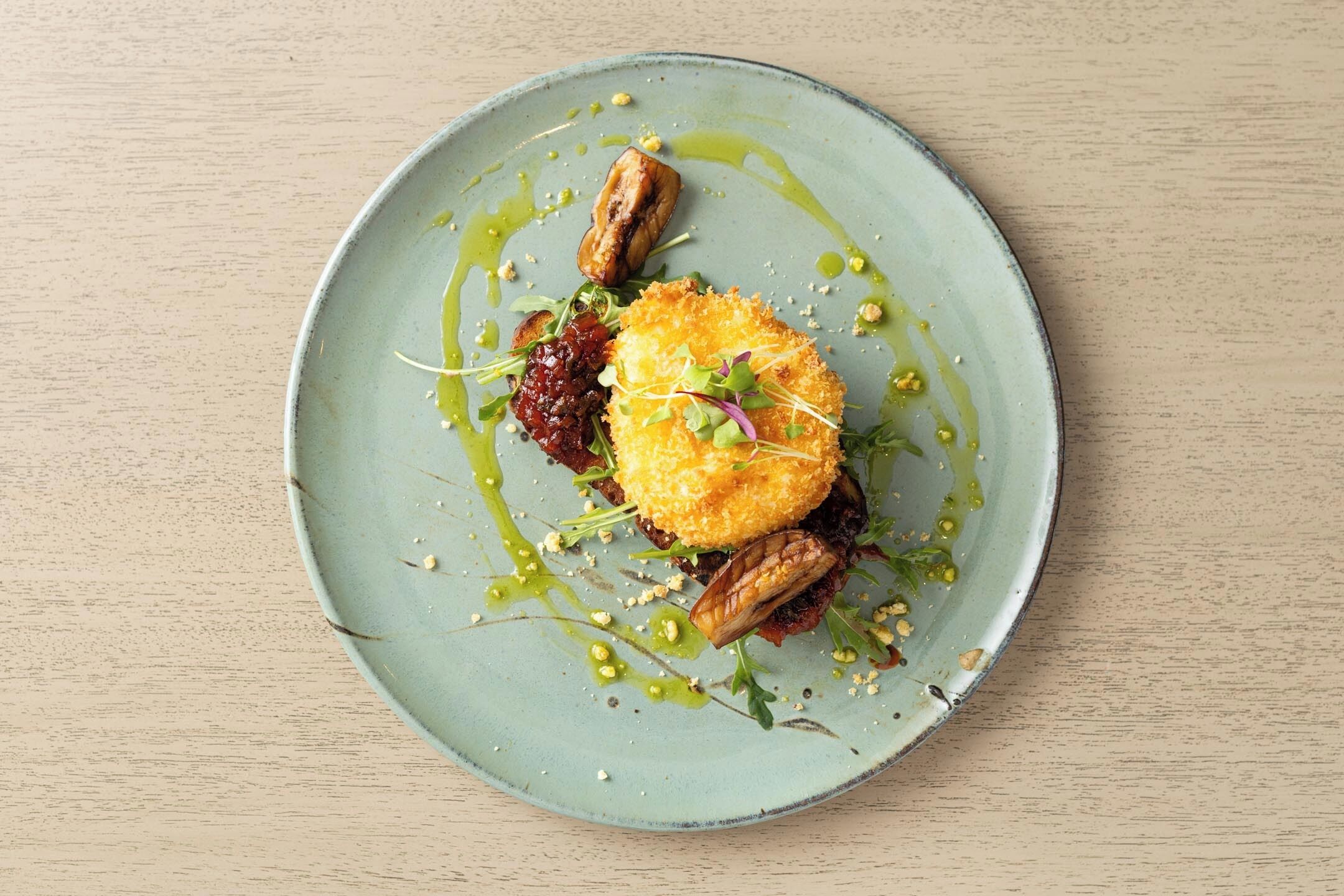 A plate with a food dish, including a crispy item, greens, and a sauce.