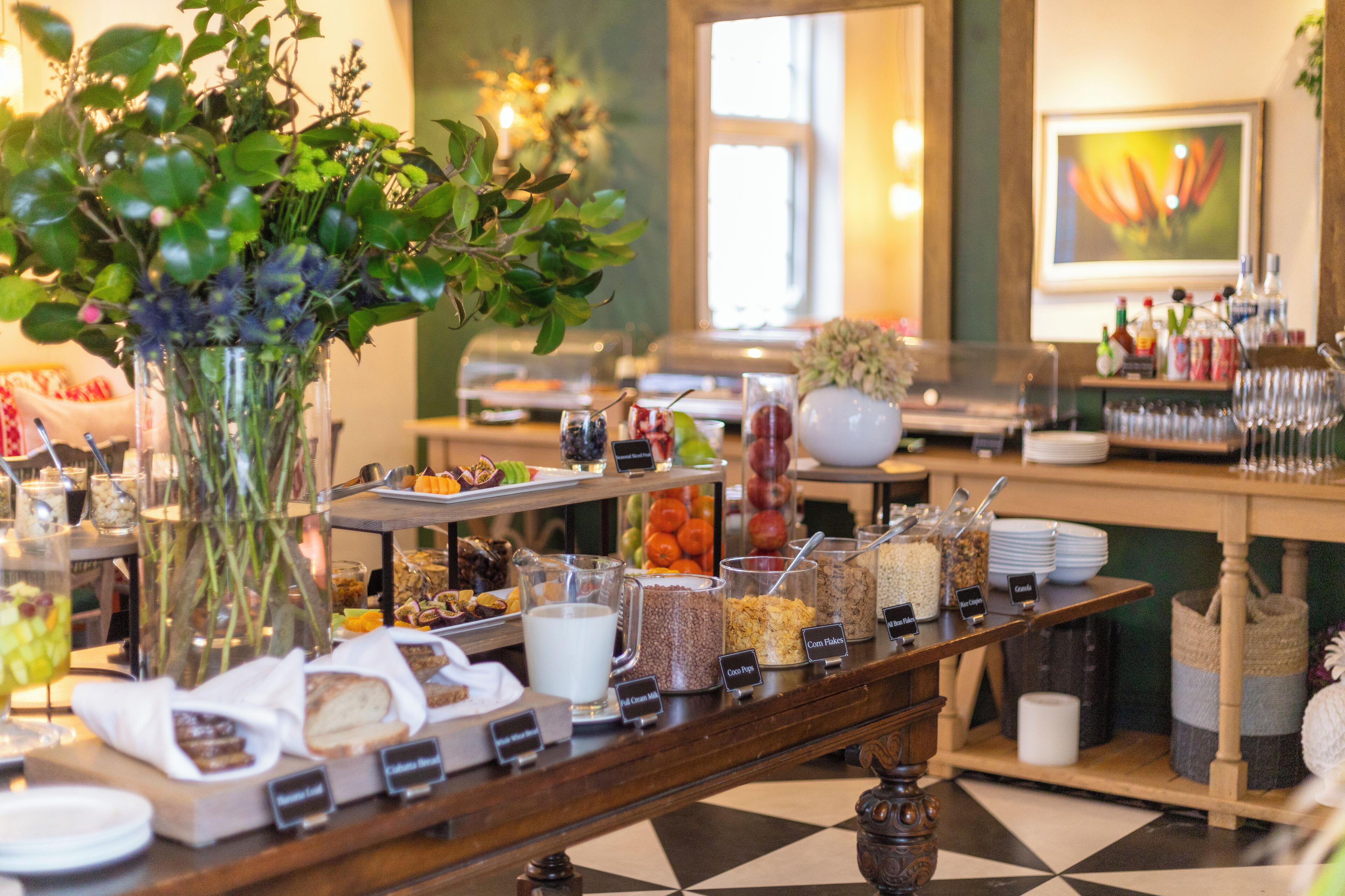 A buffet setup with various food items and a decorative vase of flowers.