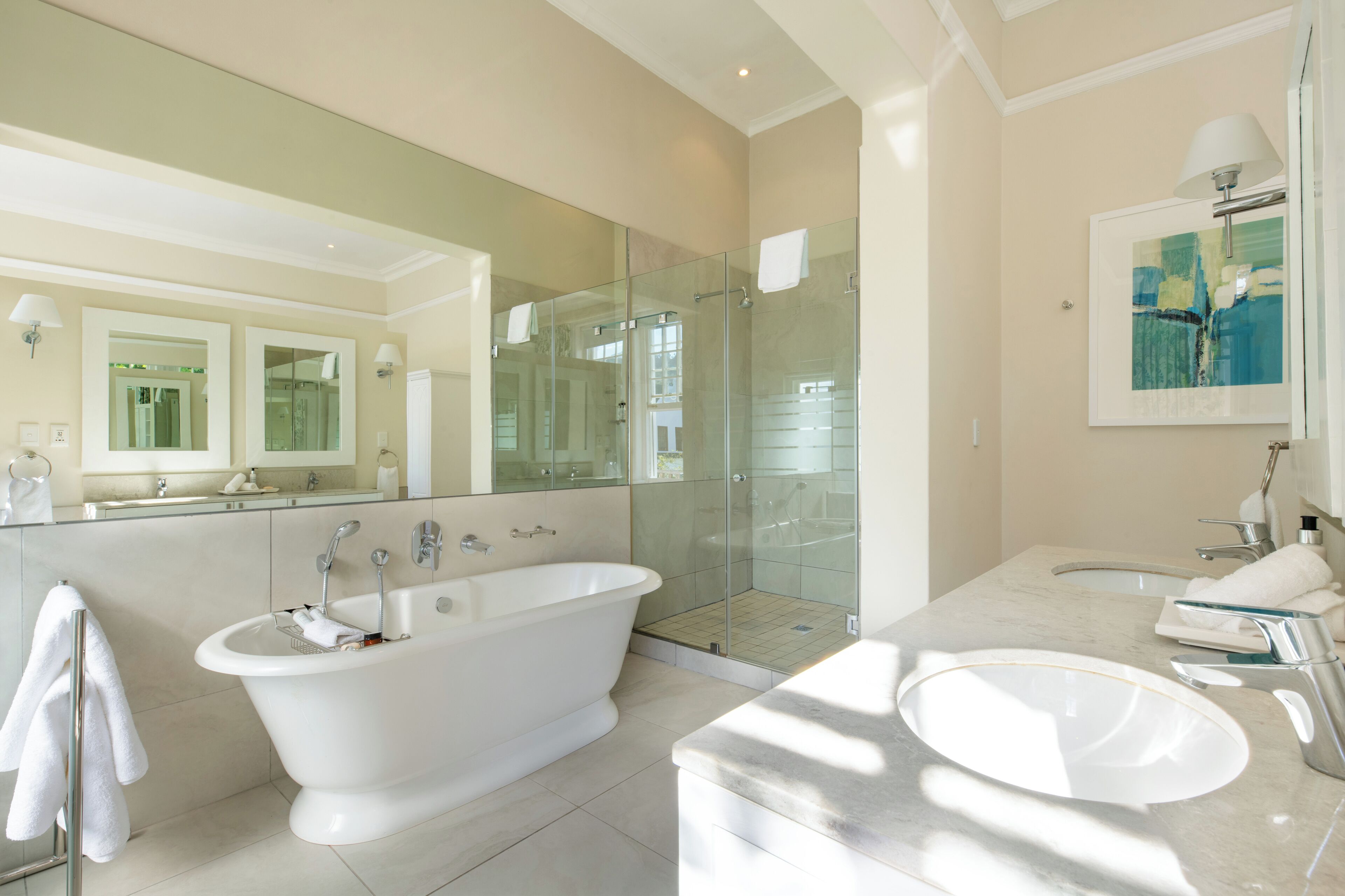 Un baño moderno con una bañera independiente, ducha con cerramiento de vidrio, lavamanos de mármol y un espejo grande.