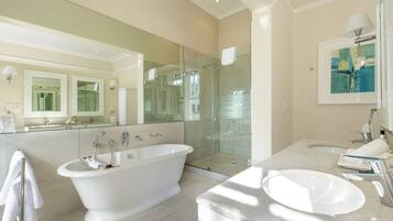 A modern bathroom with a freestanding bathtub, a glass-enclosed shower, a marble sink, and a large mirror.