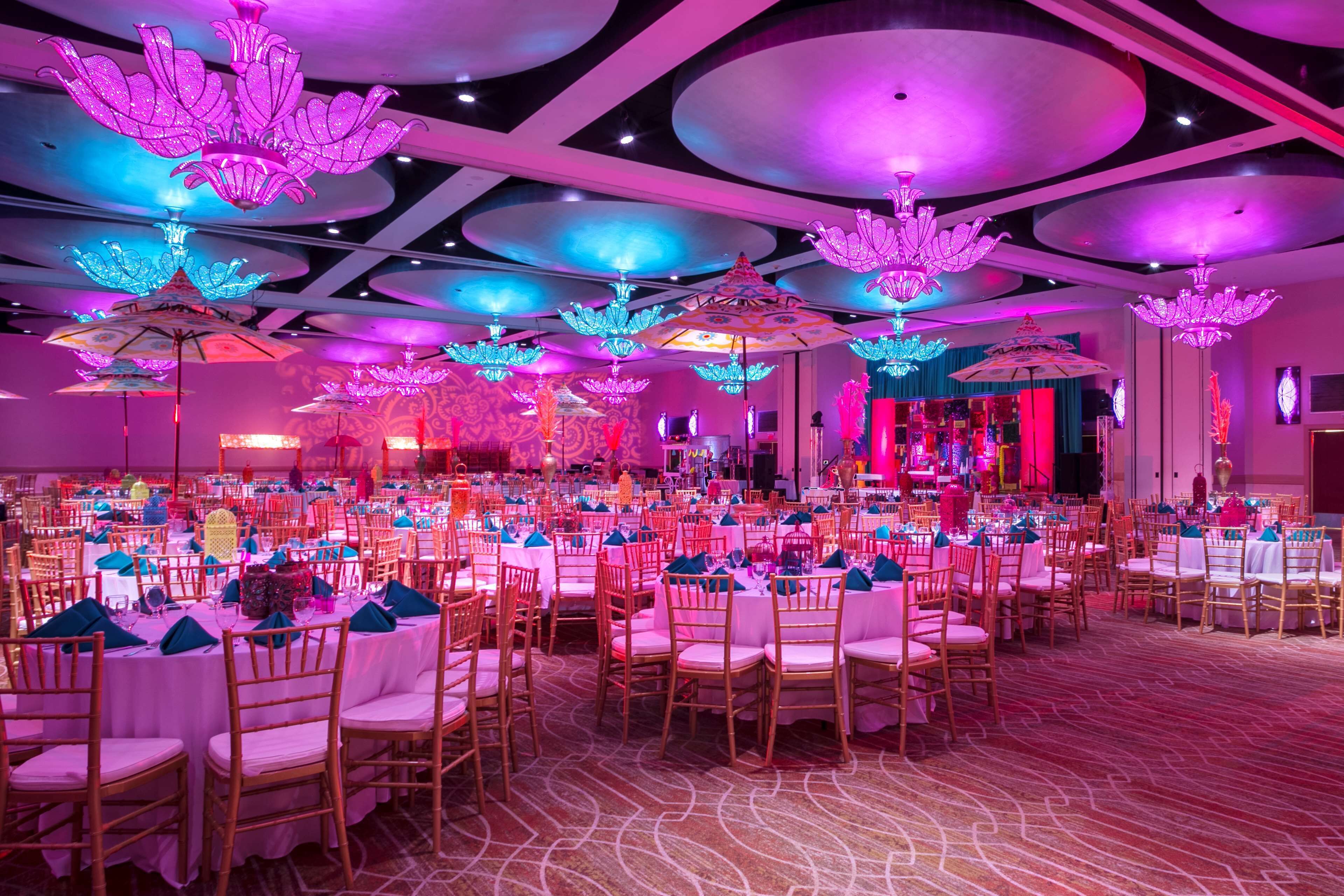 A banquet hall with round tables, chairs, and decorative lighting fixtures.