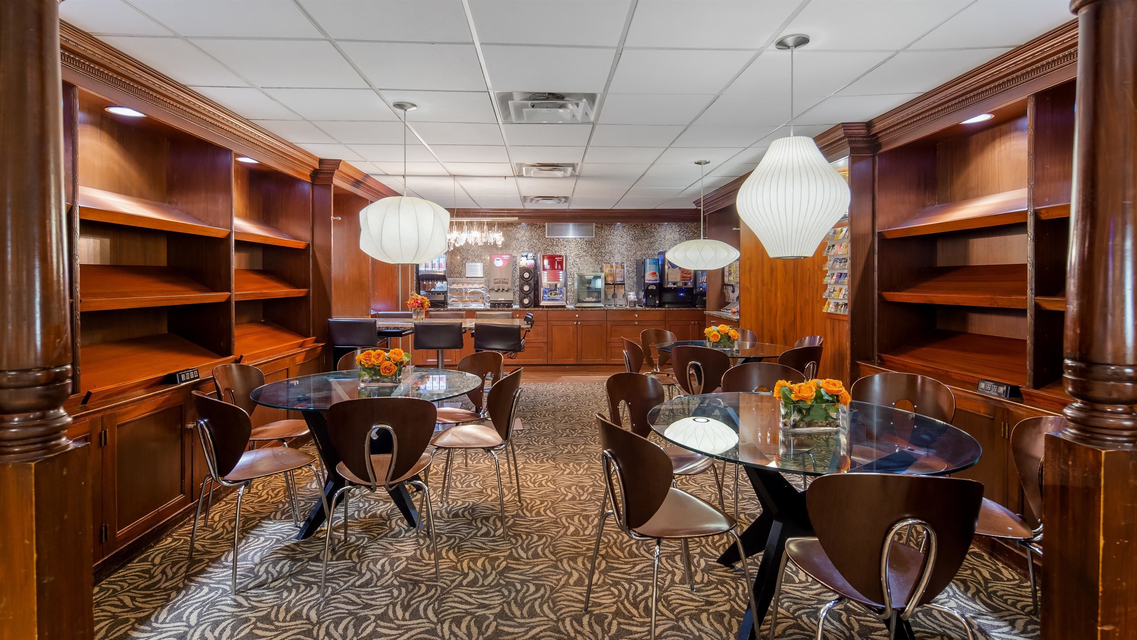 A hotel dining area with round tables, chairs, and a bar counter.
