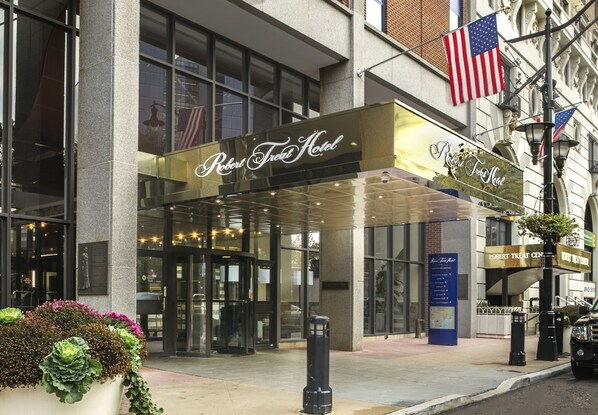 The exterior of the Robert Treat Hotel with a glass entrance, American flags, and a signboard. - Robert Treat Hotel (Newark)
