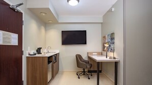 A modern kitchen with a built-in oven, a coffee maker, and a sink. There is a desk with a chair and a flat-screen TV mounted on the wall. - Springhill Suites By Marriott Orlando Altamonte Springs (Altamonte Springs)